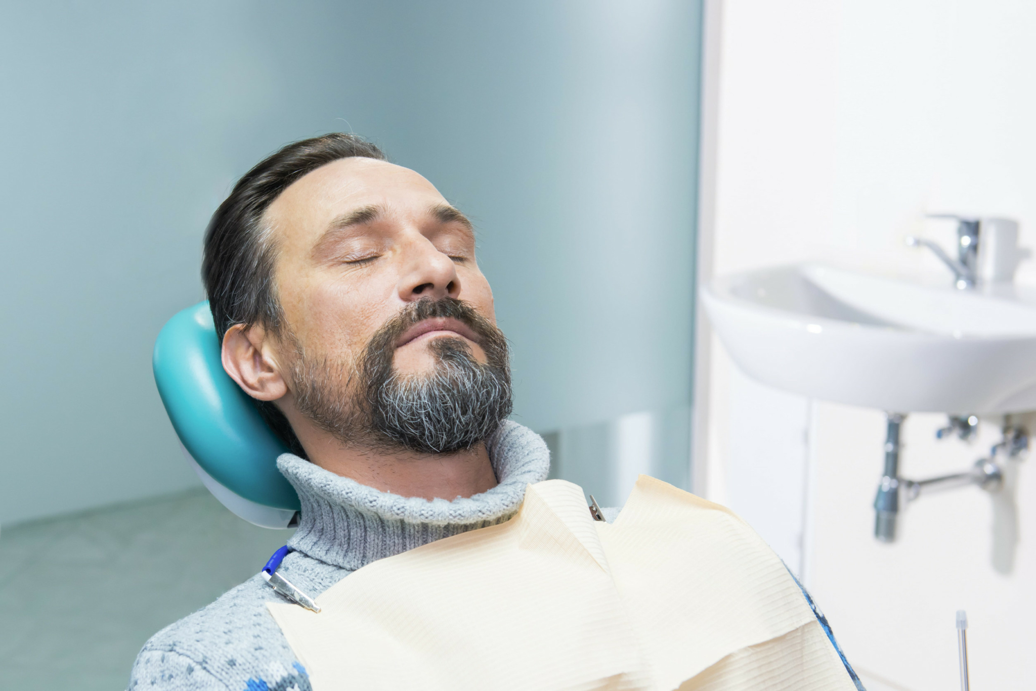 Person in dentist office. Mature mand with closed eyes.